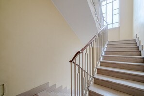 Eine Treppe mit hölzernem Geländer und Metallspindeln, die zu einer Empore mit einem Fenster führt.