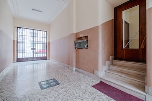 A hallway with a tiled floor, a wooden door, and a staircase. - GuestHost - A comfortable and welcoming 68 square meters apartment, perfect for four people, located on the first floor of a building (NO elevator).The property is located in the lively Borgo San Paolo neighborhood and is well connected to the city cente (Turin)