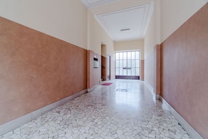 Un corridoio con pavimento decorato, una porta in fondo e una finestra vista.