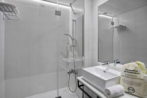 A modern bathroom with a glass-enclosed shower, a white sink, and a towel dispenser. - B&B HOTEL Figueira Da Foz (Figueira da Foz)