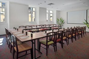 A conference room with long tables and chairs, a projector screen, and windows. - B&B HOTEL Figueira Da Foz (Figueira da Foz)