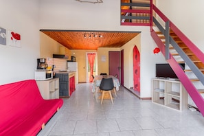 Un espacio habitable compacto con kitchenette, comedor y escalera.