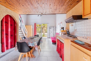 Una cocina con armarios de madera, una mesa de comedor con sillas y vistas al exterior.