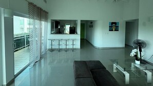 Ein modernes Wohnzimmer mit einem Glastisch, einer Couch und einer Küche im Hintergrund.