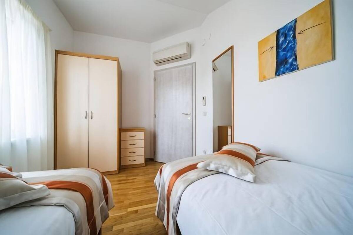 Un dormitorio con dos camas, un armario, un tocador y un espejo.