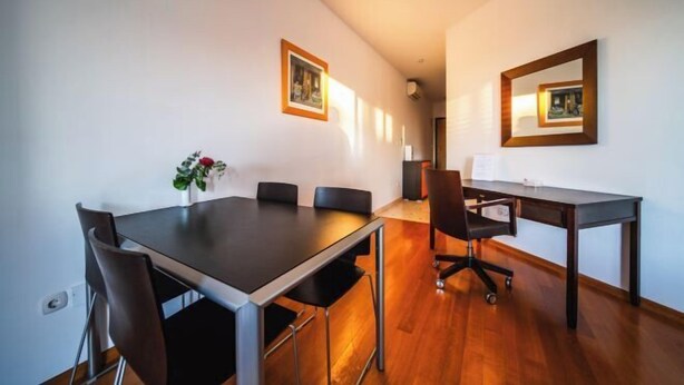 Une salle de conférence avec une longue table, des chaises, une petite table sur laquelle se trouve un ordinateur portable, et des tableaux encadrés accrochés aux murs.