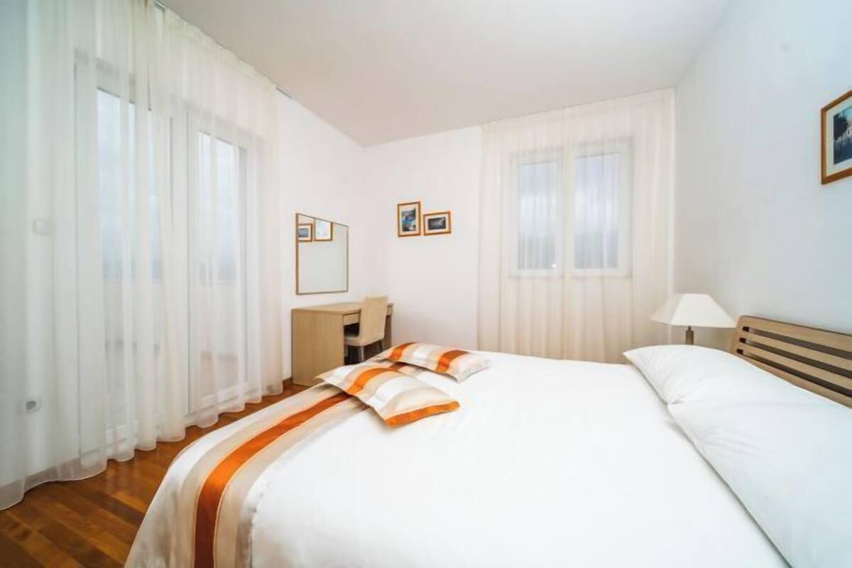 Una habitación de hotel con cama, escritorio, silla y lámpara.
