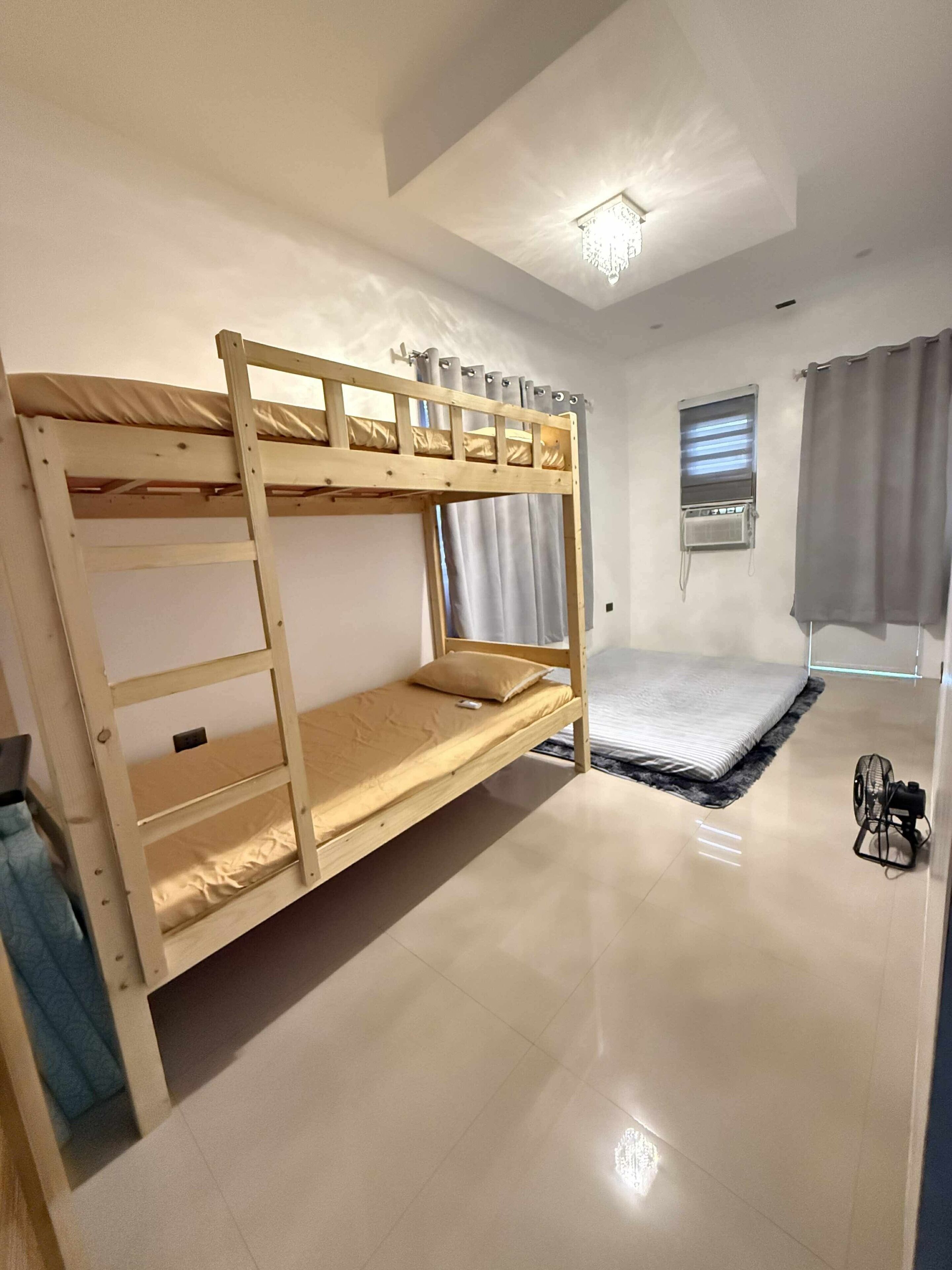 A bunk bed room with a window, a ceiling fan, and a small air conditioning unit.