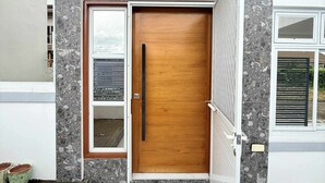 A modern entrance with a wooden door, a glass panel, and a security camera above.