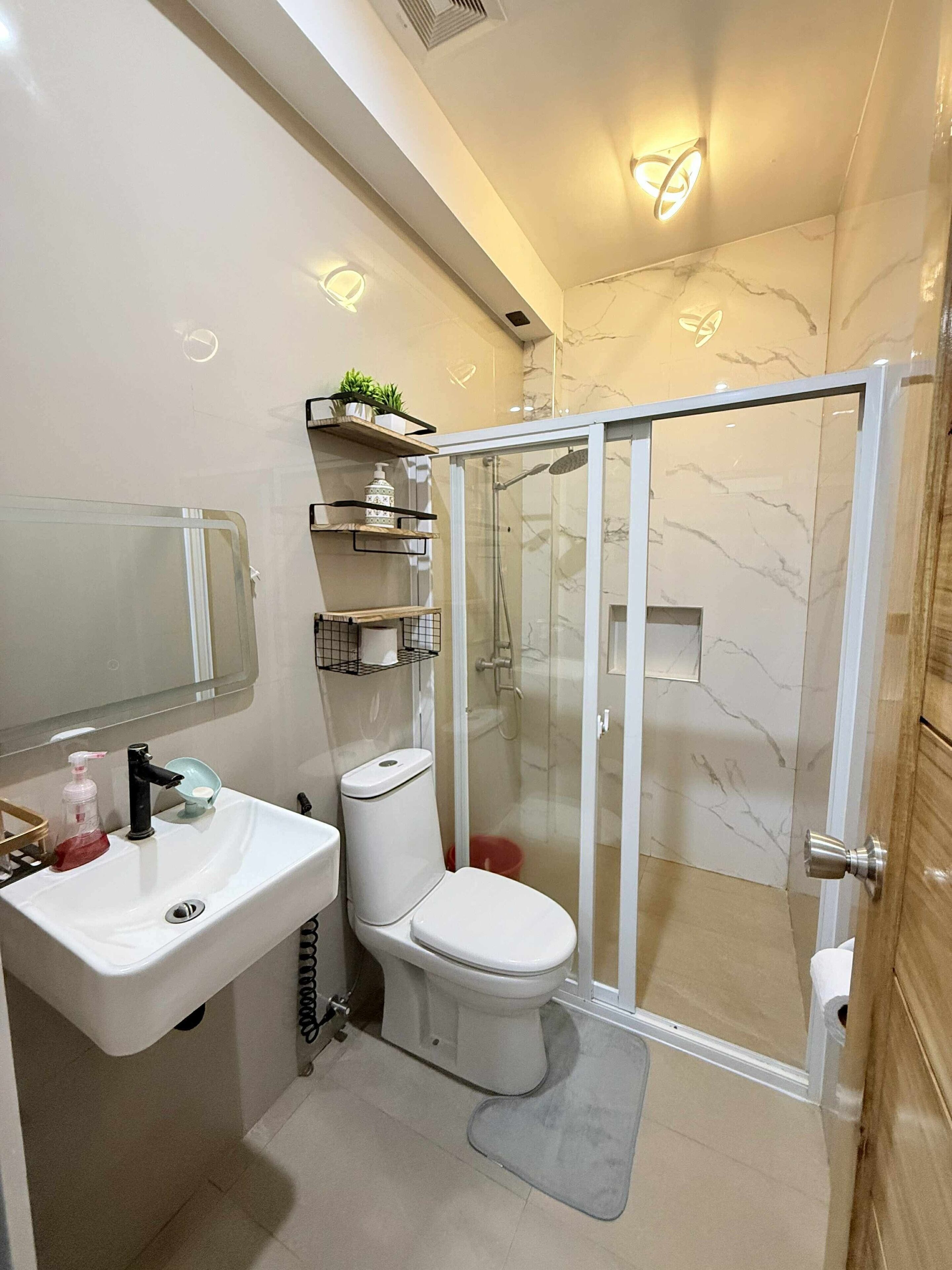 A modern bathroom with a white sink, toilet, and glass-enclosed shower.