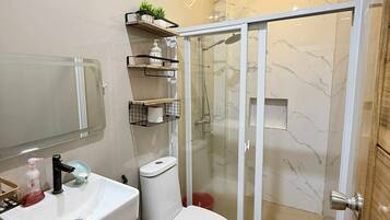 A modern bathroom with a white sink, toilet, and glass-enclosed shower.