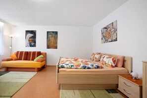 Un dormitorio con sofá, cama, mesita de noche y dos cuadros colgados en la pared.