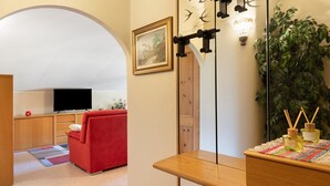 Uma sala de estar moderna com um sofá vermelho, uma televisão, uma mesa de madeira com objetos decorativos, um espelho grande e uma planta verde.