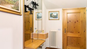 Um quarto com um banco de madeira, um espelho, um radiador e duas portas.