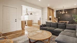 Una sala moderna con un sofá seccional gris, una mesa de centro redonda de mimbre y suelo de madera.