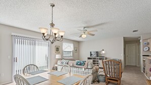 A dining area with a wooden table and chairs, a chandelier, and a ceiling fan. - 2/2 Patio Villa in De La Vista (The Villages)