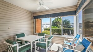 A sunlit patio with a table and chairs, a ceiling fan, and a view of the neighborhood. - 2/2 Patio Villa in De La Vista (The Villages)