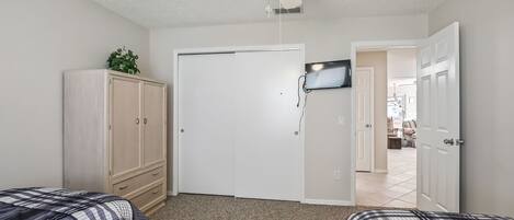 A bedroom with two beds, a ceiling fan, a TV, and a wardrobe.