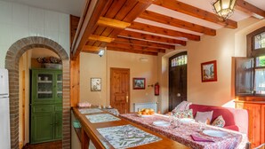 A dining area with a long wooden table, green cabinets, and a red sofa.