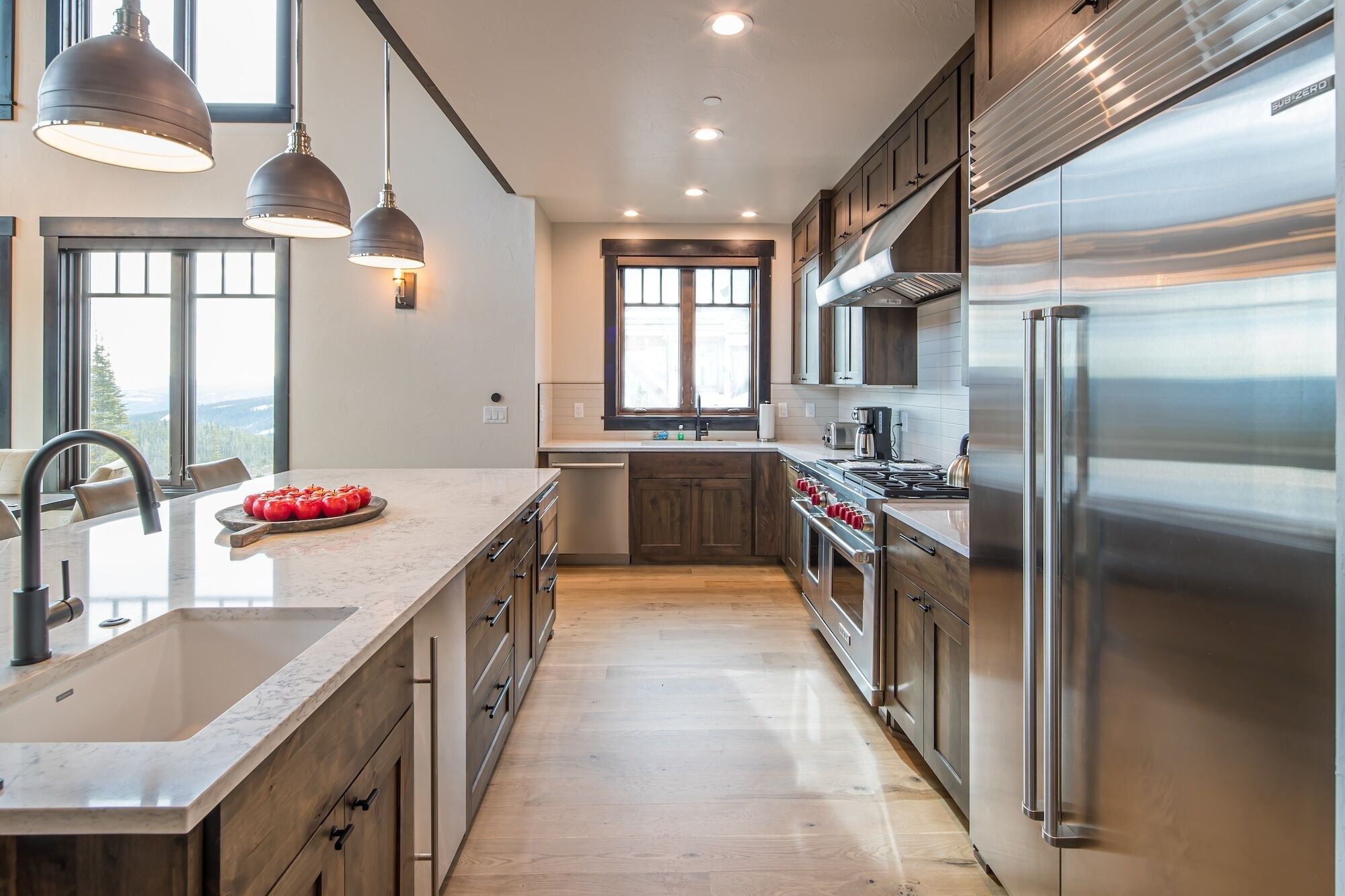 A modern kitchen with a large island, stainless steel appliances, and wooden cabinets.