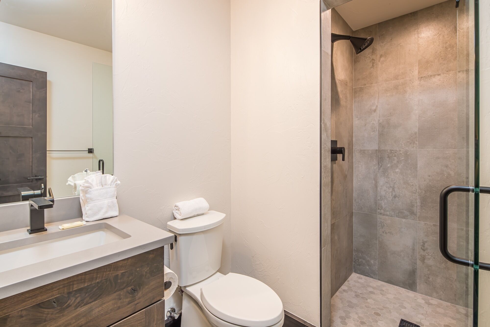 A modern bathroom with a shower, toilet, and sink.