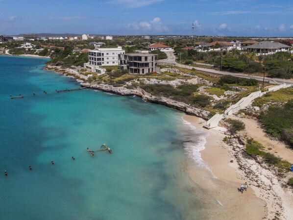 Um imóvel costeiro com praia, costa rochosa e um edifício de vários andares.