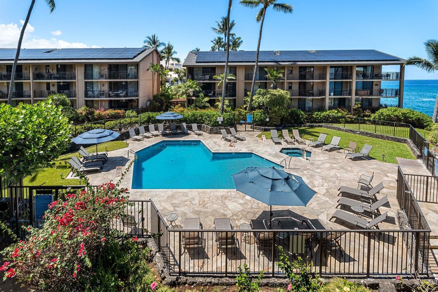 A resort with a central pool, sun loungers, and a view of the ocean.