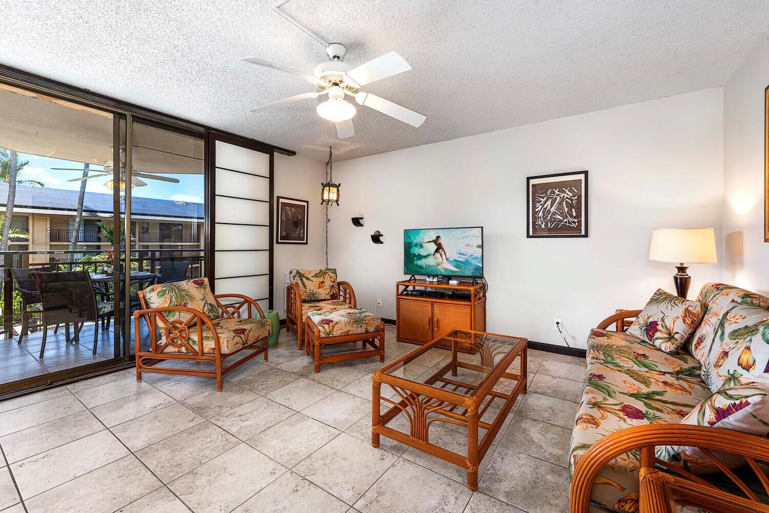 A living room with a ceiling fan, a television, and a sofa.