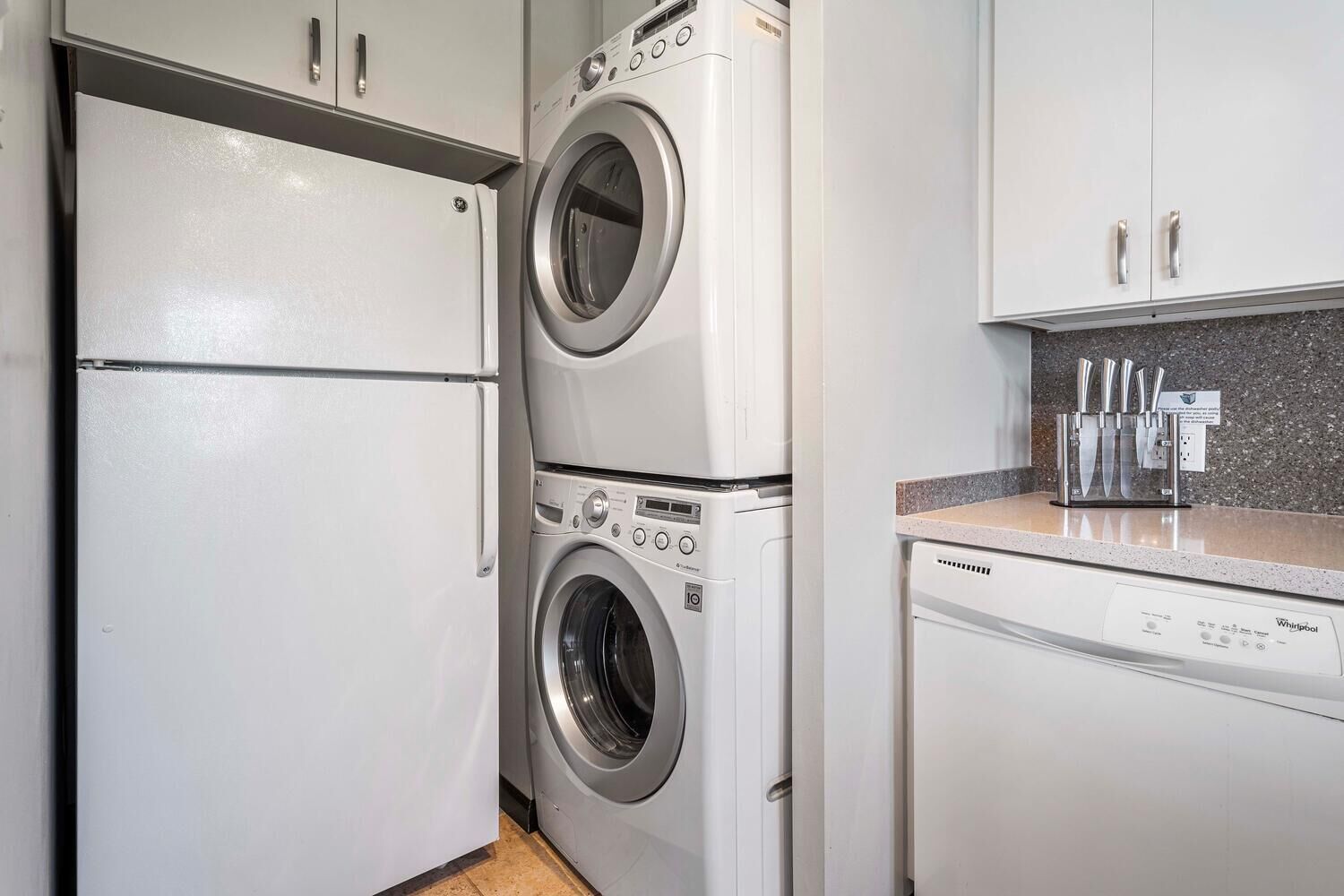 A compact kitchen with a built-in washer and dryer, a countertop with knives, and a dishwasher.