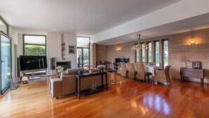 Ein geräumiges Wohnzimmer mit Kamin, Esstisch mit Stühlen und Fernseher.