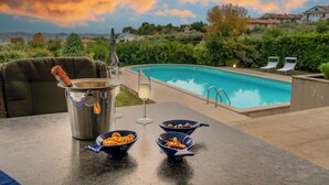 Ein Poolbereich mit Tisch, einer Champagnerflasche und Schalen mit Snacks.