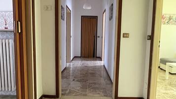 A hallway with a tiled floor, wooden doors, and a light fixture on the ceiling.