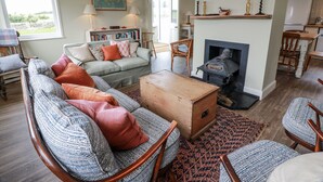 A cozy living room with a fireplace, a sofa set, a wooden coffee table, and a bookshelf. - The Dairy (Newton Stewart)