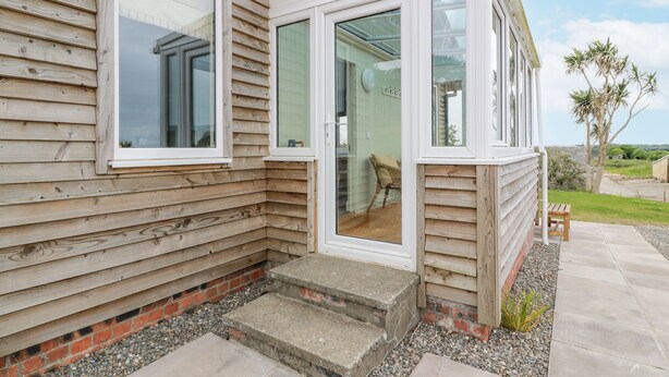 A wooden house with large windows and a small porch. - The Dairy (Newton Stewart)