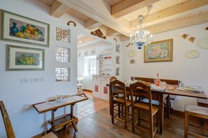 Un comedor con muebles de madera, una araña y adornos en las paredes, incluyendo cuadros y paneles decorativos.