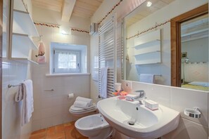 Un baño con inodoro, bidé, lavamanos y espejo.