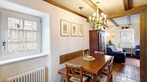 A dining area with a wooden table, chairs, a chandelier, and framed botanical prints on the wall. - Apartment 'Chalet San Valentino' with Mountain View, Shared Garden and Wi-Fi (Livigno)