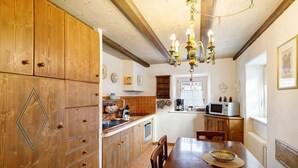 A kitchen with wooden cabinets, a dining table, and a chandelier. - Apartment 'Chalet San Valentino' with Mountain View, Shared Garden and Wi-Fi (Livigno)