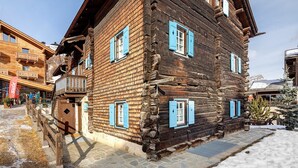 A wooden building with blue shutters, a stone staircase, and a snow-covered ground. - Apartment 'Chalet San Valentino' with Mountain View, Shared Garden and Wi-Fi (Livigno)