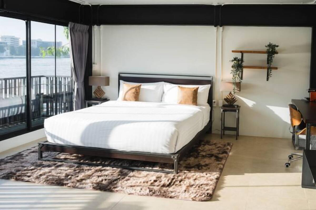 Un dormitorio moderno con una cama grande, vista al agua y un balcón.