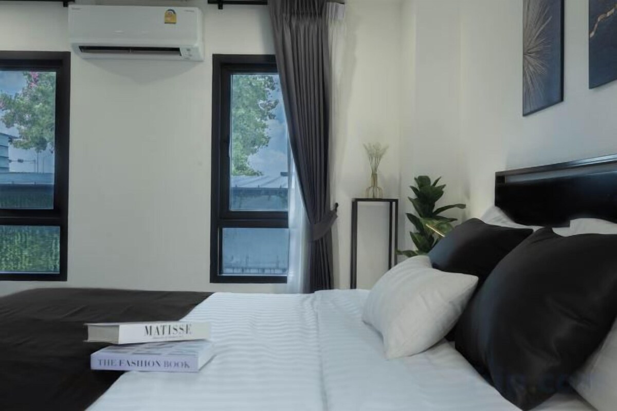 A hotel room with a bed, a bedside table, a lamp, and a window with curtains.