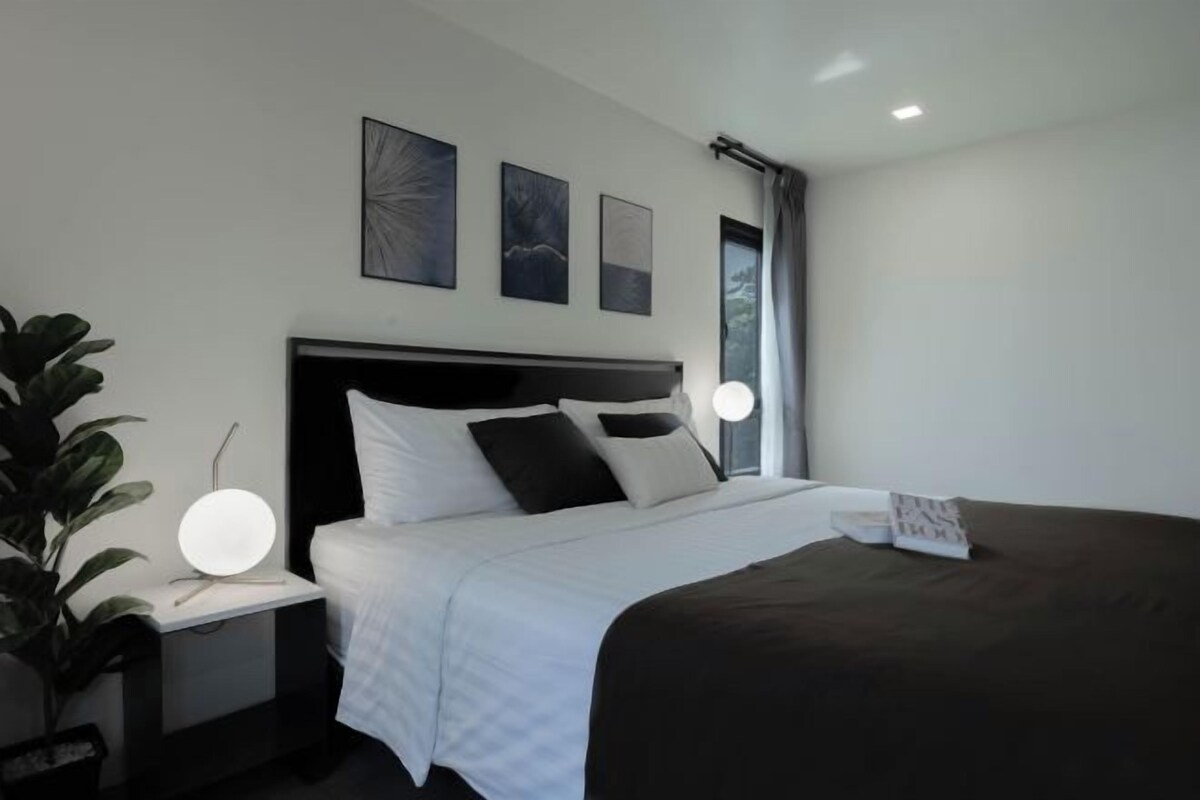 Un dormitorio moderno con una cama grande, mesitas de noche y una lámpara de noche.