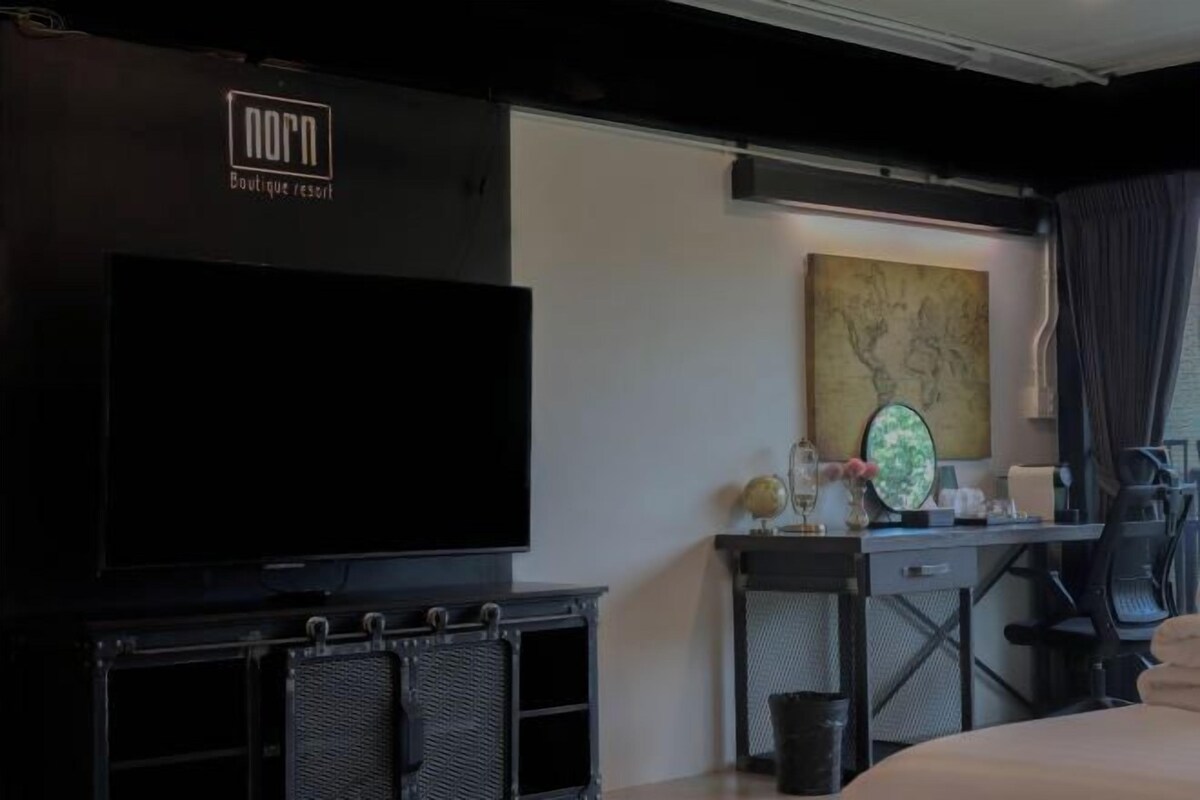 Habitación de hotel con televisión de pantalla plana, escritorio con computadora, una silla y una cama.