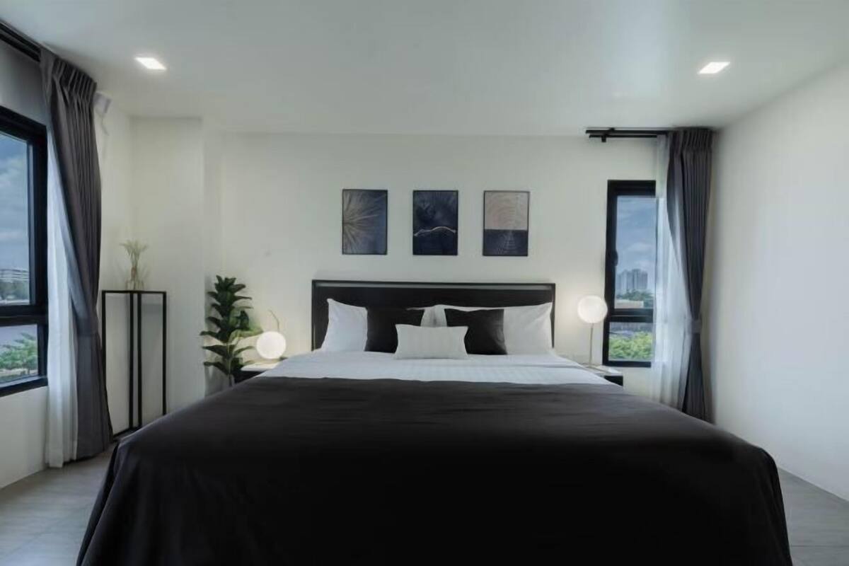 Un dormitorio moderno con una cama grande, una mesita de noche, una lámpara de pie y tres obras de arte colgadas en la pared.