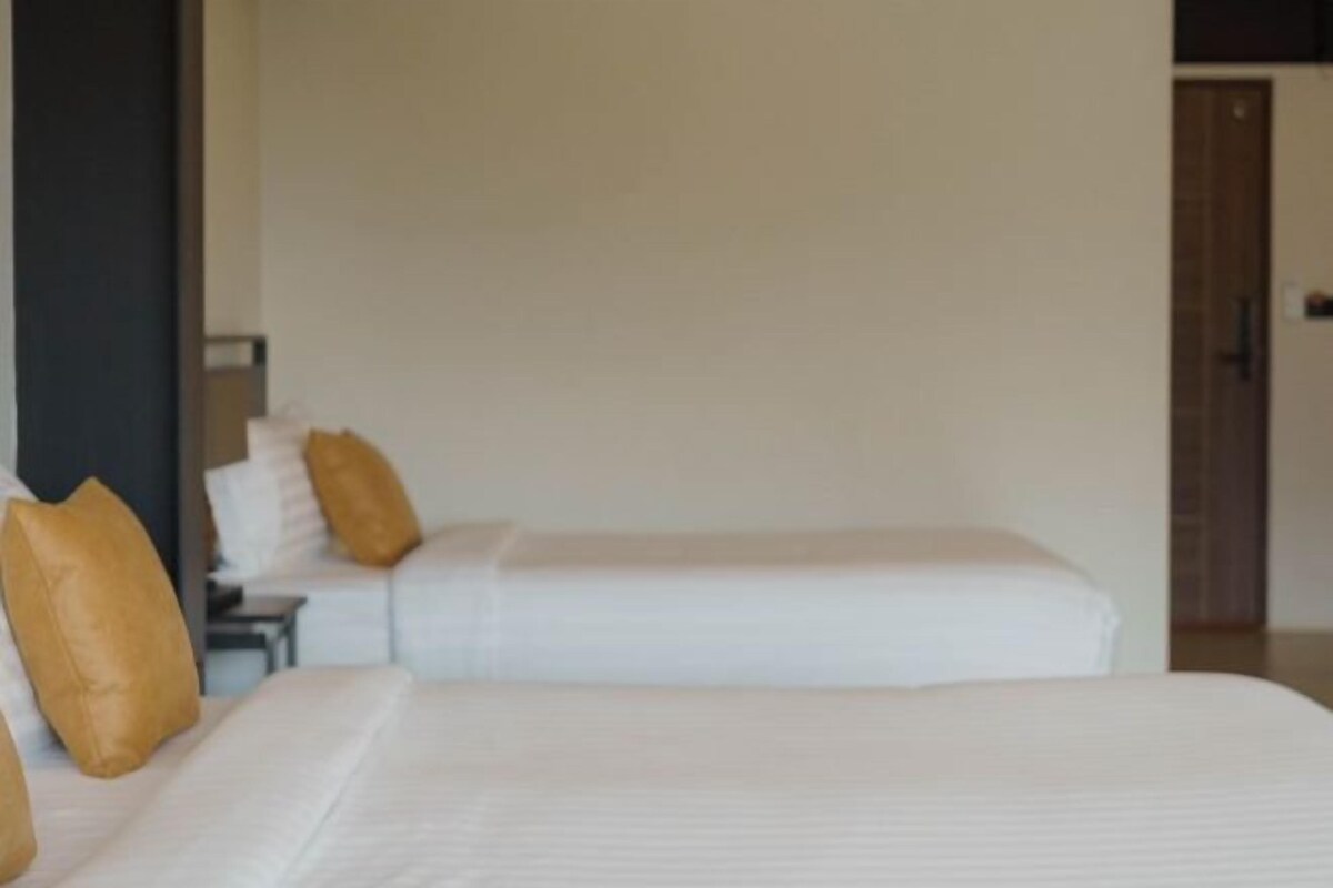 A hotel room with two beds, each with white linens and brown pillows.