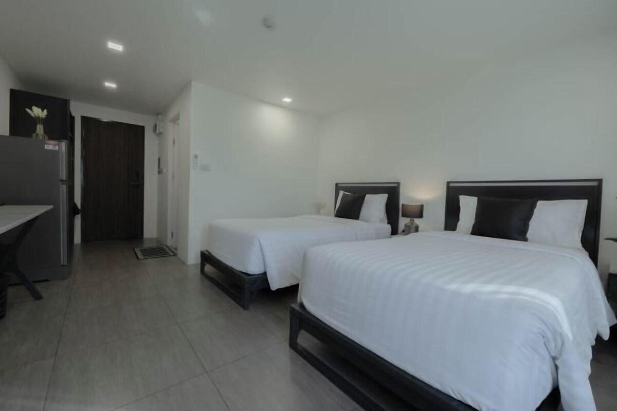 A hotel room with two single beds, a desk, and a chair.
