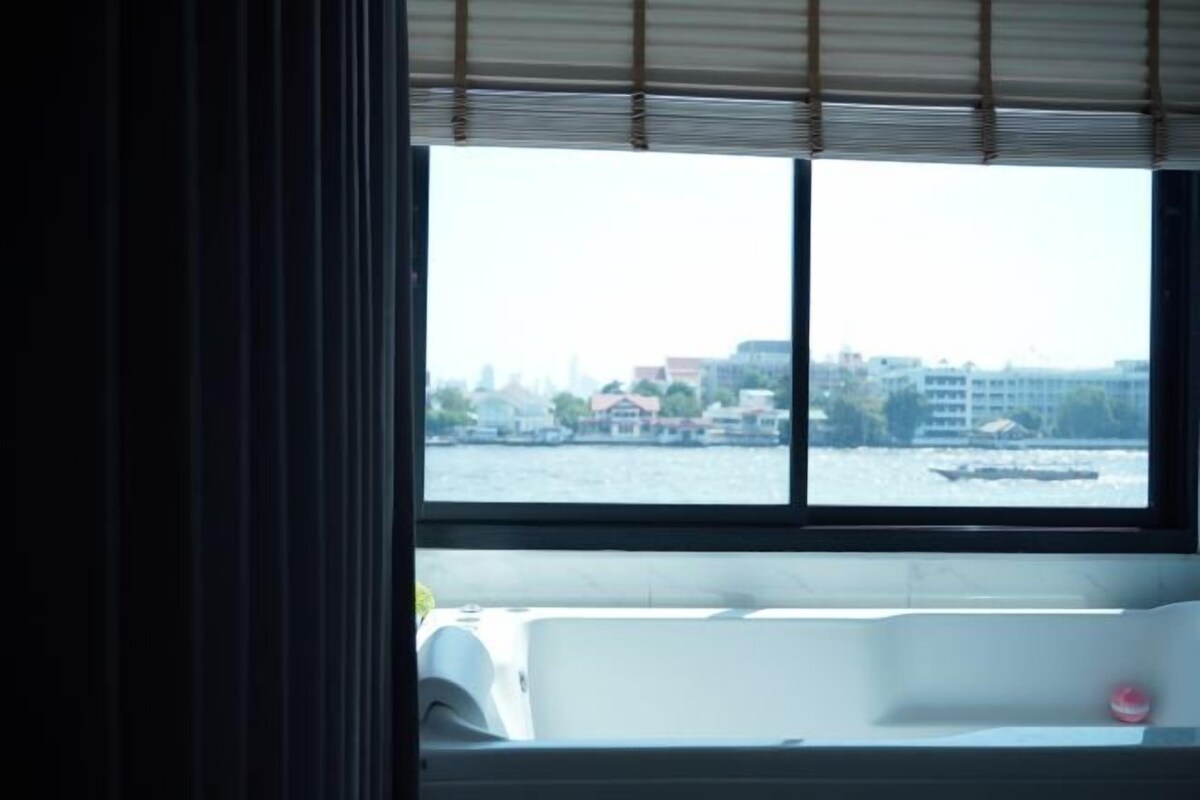 A room with a large window overlooking a body of water and a cityscape.