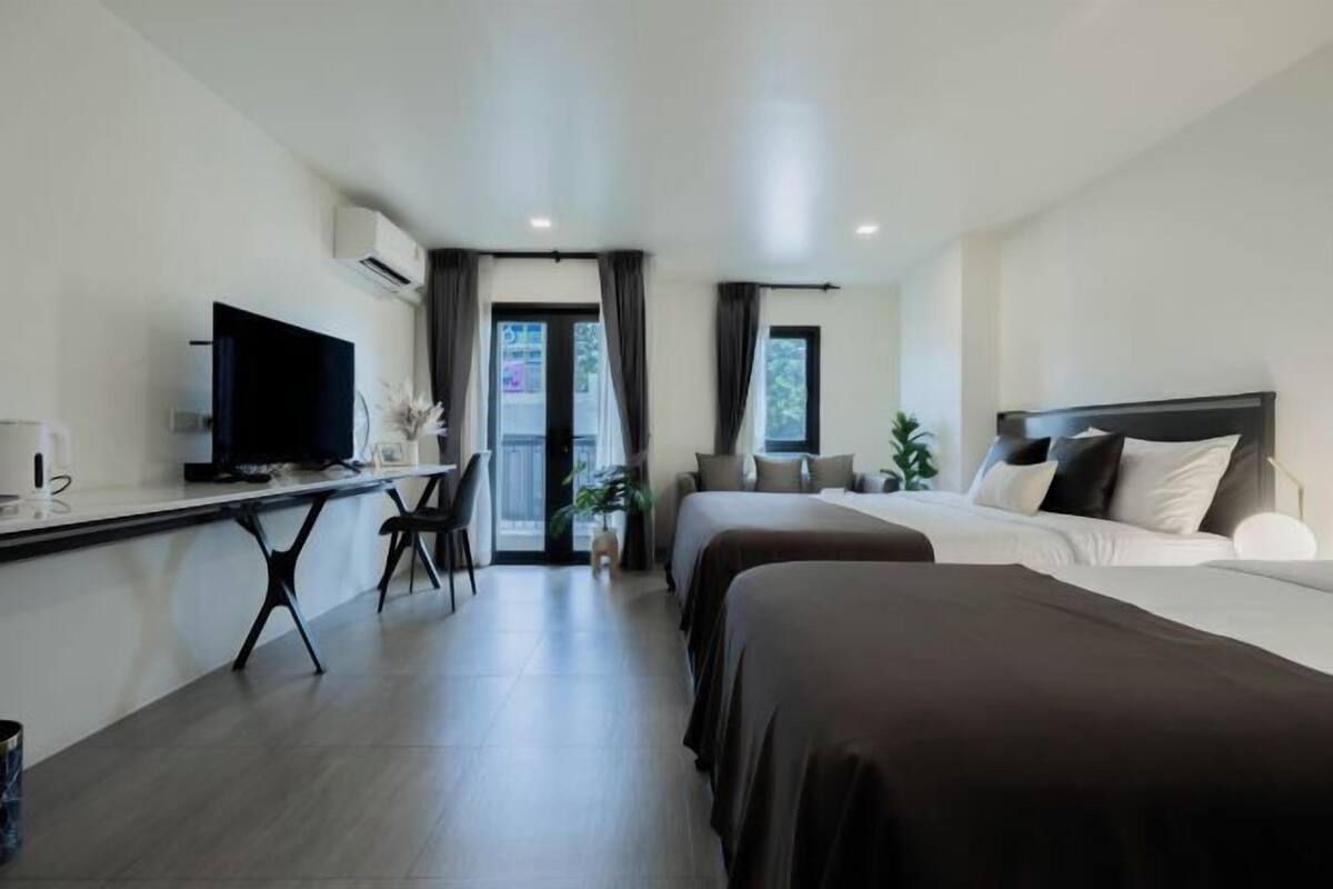 Una habitación de hotel con cama, escritorio con televisor, silla y ventana.
