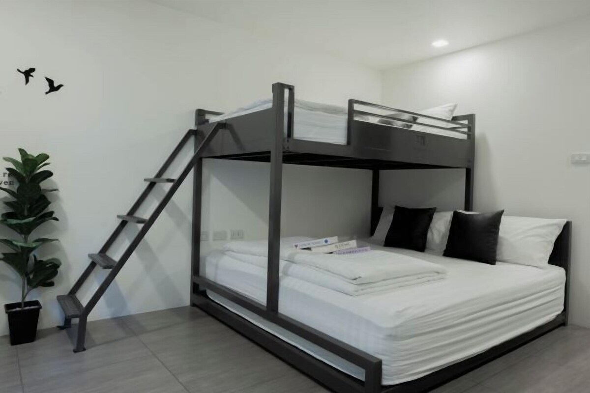 A bunk bed with a ladder, white bedding, and black pillows.