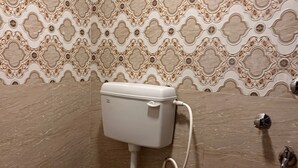 Un baño con inodoro, bidé y dispensador de papel higiénico.